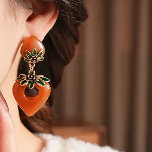 Vintage amber resin heart earrings with green enamel leaf details in a retro aesthetic