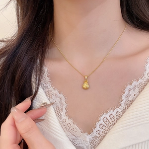 Macro shot of a gold lucky bag pendant necklace with zircon inlay on female model
