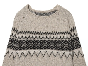 Close-up of oatmeal knit sweater featuring detailed Fair Isle geometric patterns on chest