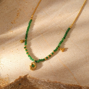 Macro detail of bohemian beaded necklace with green stone and gold lava pendant