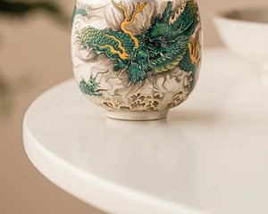 Macro detail of the green and yellow dragon pattern on a premium ceramic teacup