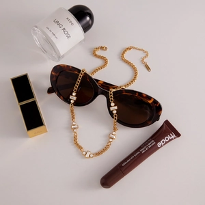 Collier en or chic avec cristaux blancs carrés et ronds présenté avec des objets de luxe