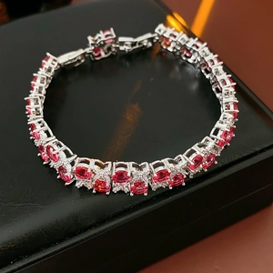 Makro-Detail eines roten ovalen Edelsteins auf Silberarmband auf einer schwarzen Box