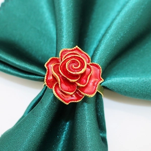 Close-up of red rose napkin ring with gold edges on a dark green silk napkin