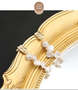 Detailed shot of baroque pearl tassel earrings hanging on a vintage gold mirror frame