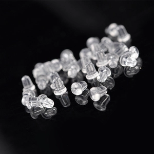 Macro shot of bulk clear silicone earring back stoppers on a reflective black background