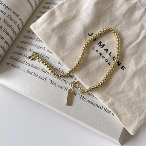 Detailed macro view of S925 sterling silver golden bead bracelet with square metal tag