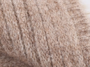 Makroaufnahme von beigem Grobstrickgewebe mit weicher Mohair-Wollstruktur für Winter