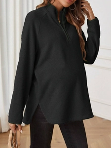Detail of maternity top featuring a quarter-zip stand collar and side slit in black fabric