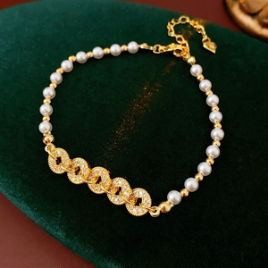 Elegant gold pearl bracelet with zircon coin charms on green velvet background