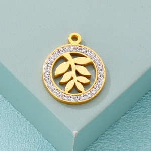 Gold stainless steel round pendant with hollow leaf pattern and pavé crystals on green stand