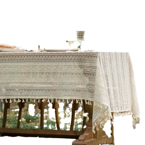 Beige lace tablecloth with vintage crochet flowers and fringe edges on a wooden table