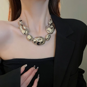 Macro view of silver metallic necklace featuring irregular melted-effect oval links