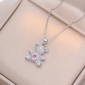 Détail macro du pendentif ours argenté avec zircon cœur rose sur boîte à bijoux cuir