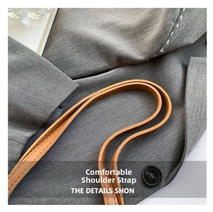 Close-up of gray textured canvas fabric with decorative stitching and brown leather strap