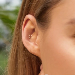 Close-up of a gold S925 sterling silver star-shaped stud with cubic zirconia on ear