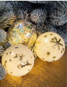 Macro view of Christmas bulb ornaments with warm LED light and reindeer patterns