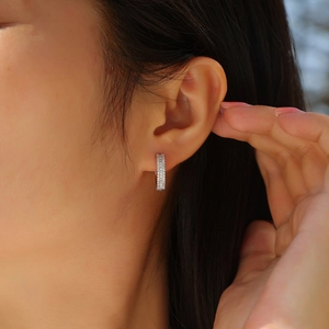 Close-up of silver hoop earrings featuring double rows of sparkling moissanite stones on ear