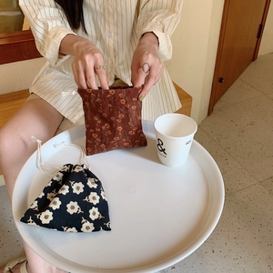 Detalle de bolsas de pana con cordón y estampados florales sobre una bandeja blanca