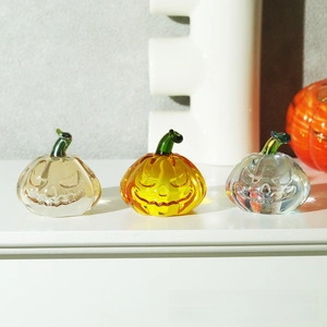 Three crystal pumpkin ornaments in yellow and clear glass with vivid carved faces