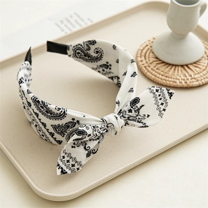 Dettaglio del cerchietto largo in tessuto bianco con stampa paisley e fiocco annodato
