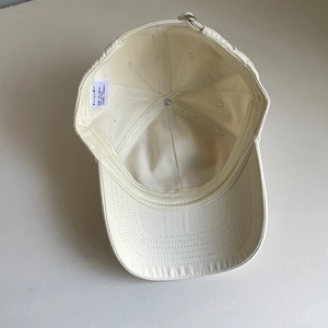 Interior view of beige cotton baseball cap showing 6-panel build and 100% cotton label
