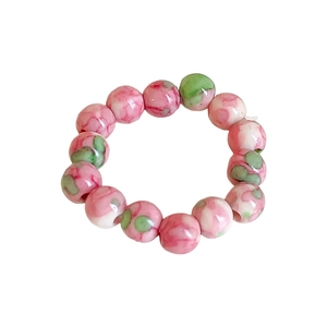 Handmade stretch ring with pink and green floral glass beads on white background