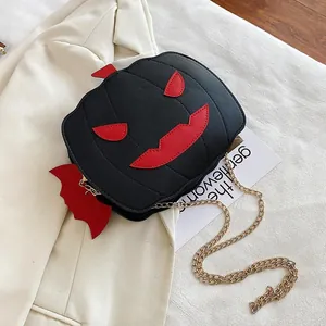 Close-up of Halloween pumpkin bag with bat wings and gold chain on neutral background