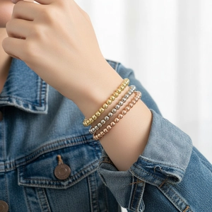 Detailed view of stacked 18K gold-plated beaded elastic bracelets in three metallic colors