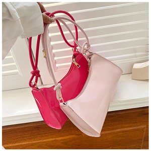 Detailed macro view of the knotted strap and glossy finish on the fuchsia hobo baguette bag