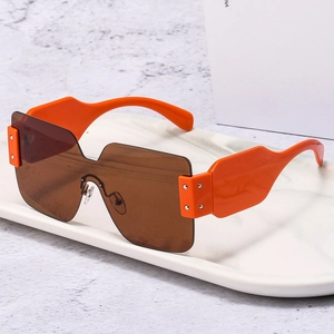 Fashionable orange wide-frame oversized sunglasses with brown lenses on a marble tray