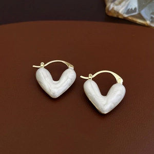 Détail macro de boucles d'oreilles cœur dorées avec texture marbre blanc sur cuir