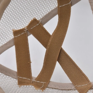 Detail of the elastic criss-cross ponytail opening on a beige mesh baseball cap