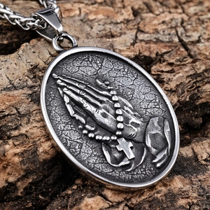 Vintage stainless steel praying hands cross pendant necklace on a rustic wood background