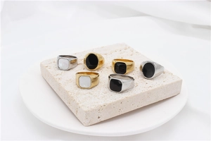 Minimalist gold and silver rings with black onyx and white shell inlays on stone