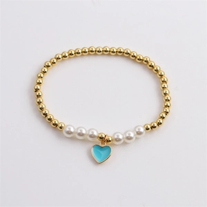 Detail of beaded bracelet featuring gold beads, white pearls, and a blue heart pendant
