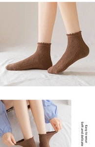 Close-up of brown cotton socks with cable knit texture and delicate lace cuffs for women