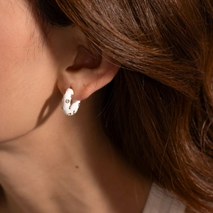 Fashionable white enamel C-shaped titanium earrings with gold trim and diamonds on model