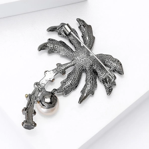 Close-up of vintage grey metal coconut tree brooch with white pearl inlay and pin back