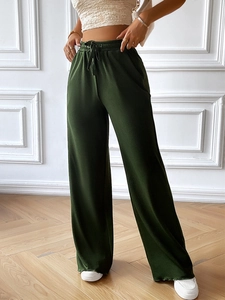 Detail of dark green wide-leg trousers featuring elastic waistband and drawstring design