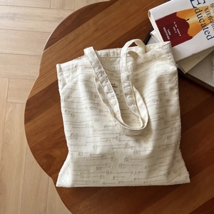 Detail shot of cream canvas tote bag with textured embossed polka dots on a wooden table