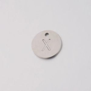 Close-up of a round silver stainless steel pendant featuring an engraved letter X