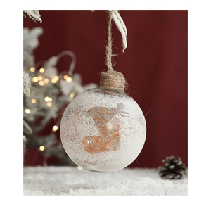 Close-up of clear Christmas ball with fake snow and dry grass inside for tree decoration