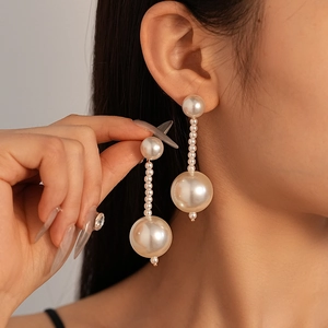 Close-up of vintage pearl tassel earrings with gold-tone accents on a model