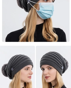 Détail d'un bonnet en maille avec boutons latéraux pour masque et grand pompon en fourrure