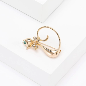 Close-up of golden cat brooch with green rhinestone eye and crystal bow tie detail