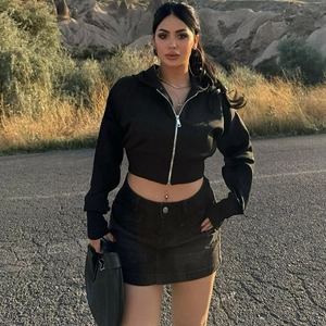 Outdoor street style shot of a black cropped zip hoodie and matching denim skirt