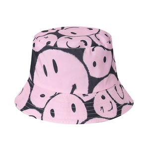 Detailed macro view of pink canvas bucket hat with repeated black smiley face pattern