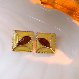 Vintage gold-plated square enamel earrings with brown leaf detail on white porcelain tray