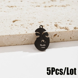 Detailed view of 5pcs black metal abstract face pendants on beige stone background